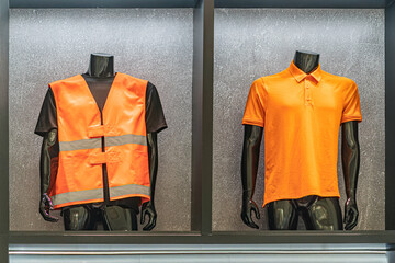 Two orange safety vests displayed on headless mannequins against a light grey background. Vests...