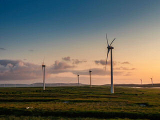 Tall powerful wind turbine in a field. Blue sky background. Production of clean renewable energy....