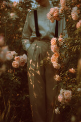 Vintage Garden Style with Roses and High-Waisted Trousers
A soft, nostalgic composition showing a young person in beige high-waisted trousers with suspenders, standing among blooming pale roses. 