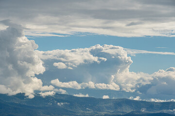 Expansive white cloudscape, varying cloud sizes, mountain range backdrop, soft lighting, low angle...