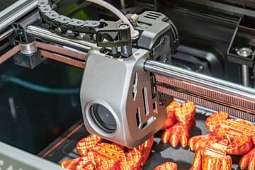 Close-up image of an orange-colored industrial process featuring a robotic arm over a conveyor belt...