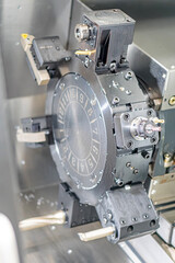 Close-up image of an industrial machinery assembly, featuring a central metallic circular component with holes and grooves Surrounding parts are cylindrical and flat, all suggesting precision engine