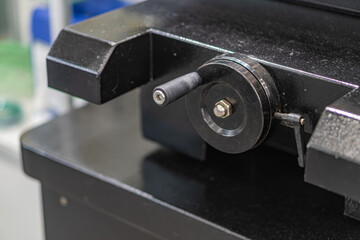 A workshop or laboratory setting features a mechanical assembly on a blue workbench The central object is a circular metal component with bolts, possibly part of an industrial equipment or precision