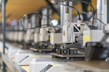 Industrial setting with a row of automated manufacturing equipment, including robotic arms, control panels, and electrical wiring Concrete floor, light-colored walls Even lighting from overhead sou