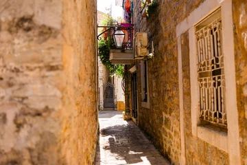Photo sur Plexiglas A narrow alley glows in the Mediterranean sun. Summer travel, architectural charm, and the intimacy of historic European streets.