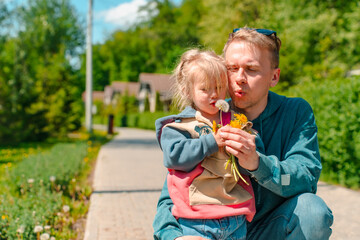 Young father with his little daughter toddler in spring with dandelions outdoor