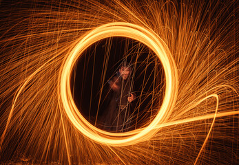 A witcher casting a magic spell in the form of a circle of fire that opens a portal and releases sparks, like in superhero films.