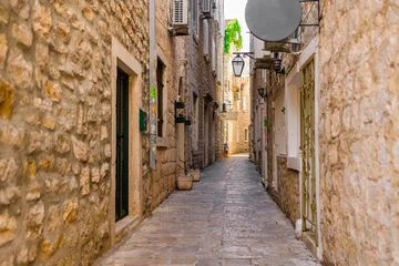 Photo sur Plexiglas Narrow historic alley with stone buildings in Mediterranean old town. Cultural heritage, summer tourism, and urban charm