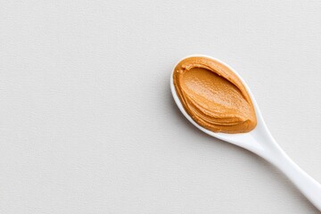 Spoon with Smooth Peanut Butter on White