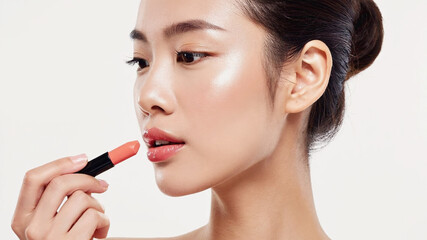 Asian woman applies coral lipstick, showcasing her smooth, radiant skin. Close-up portrait highlights beauty and elegance against white background. Image made using Generative AI