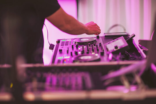 Music fills the air as a DJ spins tracks at a lively event under vibrant lights in the heart of the city