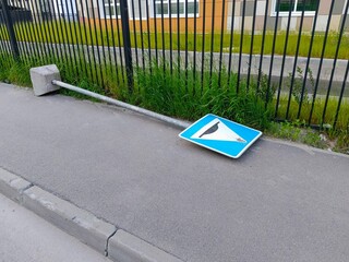 Traffic sign on the road in front of a metal fence.