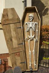 A Halloween decoration, a skeleton-like figure, is affixed to a brick wall.  The figure is...