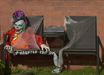 A Halloween decoration, a skeleton-like figure, is affixed to a brick wall.  The figure is composed...