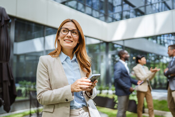 Smart businesswoman use cellphone in front of modern office building