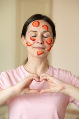 girl or young woman of European appearance makes a mask from strawberries. Expressing love and care during a natural strawberry skincare ritual