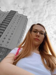 Girl in glasses on the background of the city. A girl in a white T-shirt and glasses.