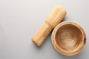Wooden mortar and pestle on light grey background, top view. Space for text