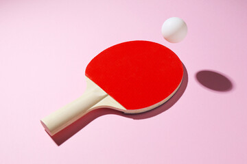 Ping pong racket and ball on pink background