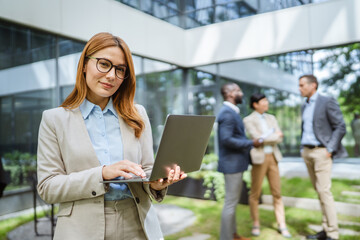 Smart businesswoman use laptop in front of modern office building
