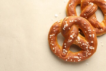 Tasty pretzels with salt on beige background, flat lay. Space for text