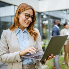 Smart businesswoman use laptop in front of modern office building