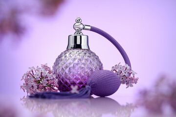 Bottle of perfume and lilac flowers on mirror surface against violet gradient background, selective...