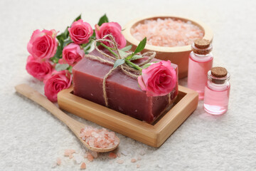 Soap bar, sea salt and beautiful roses on beige table, closeup