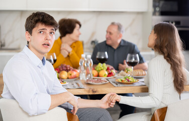 Upset young guy at family holiday table with parents at home. Unpleasant discussion