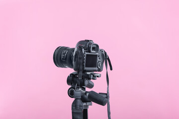 Modern professional video camera on pink background