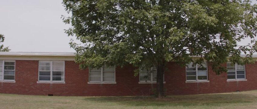 Historic school building under a large tree