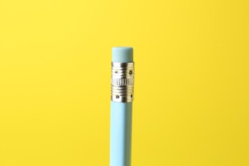 One graphite pencil with eraser on yellow background, closeup