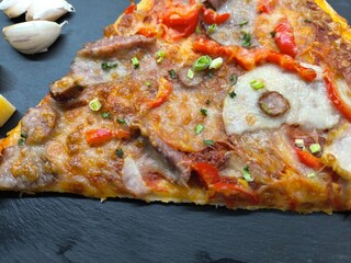delicious slice of pizza lies on the table on a sliced board.