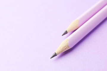 Two graphite pencils on violet background, closeup. Space for text