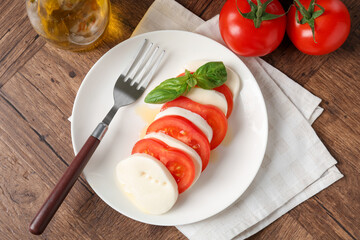 Tasty mozzarella, tomatoes, oil and basil on wooden table, flat lay