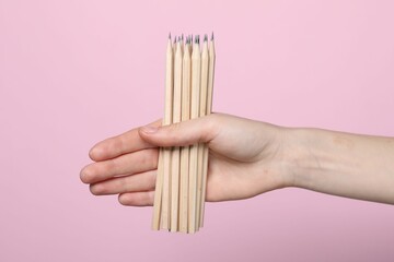Woman with graphite pencils on pink background, closeup