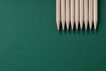 Many graphite pencils on green background, flat lay. Space for text