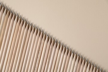 Many graphite pencils on beige background, flat lay. Space for text