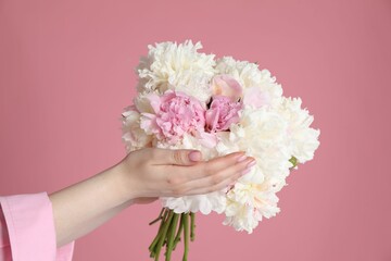 Woman with bouquet of beautiful peonies on pink background, closeup