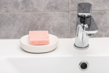 Soap bar near faucet on sink in bathroom, closeup