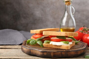 Tasty sandwiches with mozzarella cheese, tomatoes and basil on wooden table, closeup. Space for text