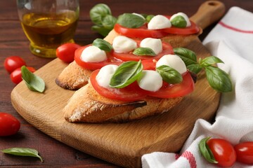 Tasty sandwiches with mozzarella cheese, tomatoes and basil on wooden table, closeup