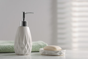 Soap bar, bottle of cosmetic product and towel on white table indoors