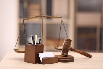 Judge's gavel, scales and stationery on wooden table in office
