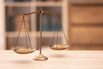 Scales of justice on wooden table in office, space for text