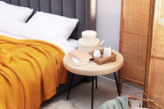 Side table with books and decor near bed indoors