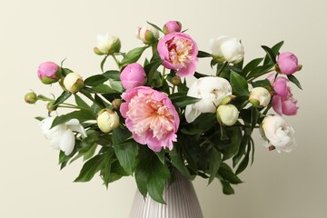 Bouquet of beautiful peony flowers in vase on beige background