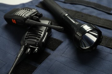 Flashlight and walkie talkies on bulletproof vest, closeup. Police equipment