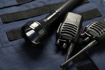 Flashlight and walkie talkies on bulletproof vest, closeup. Police equipment