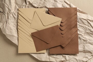 Beautiful invitation envelopes and parchment paper on carton, top view